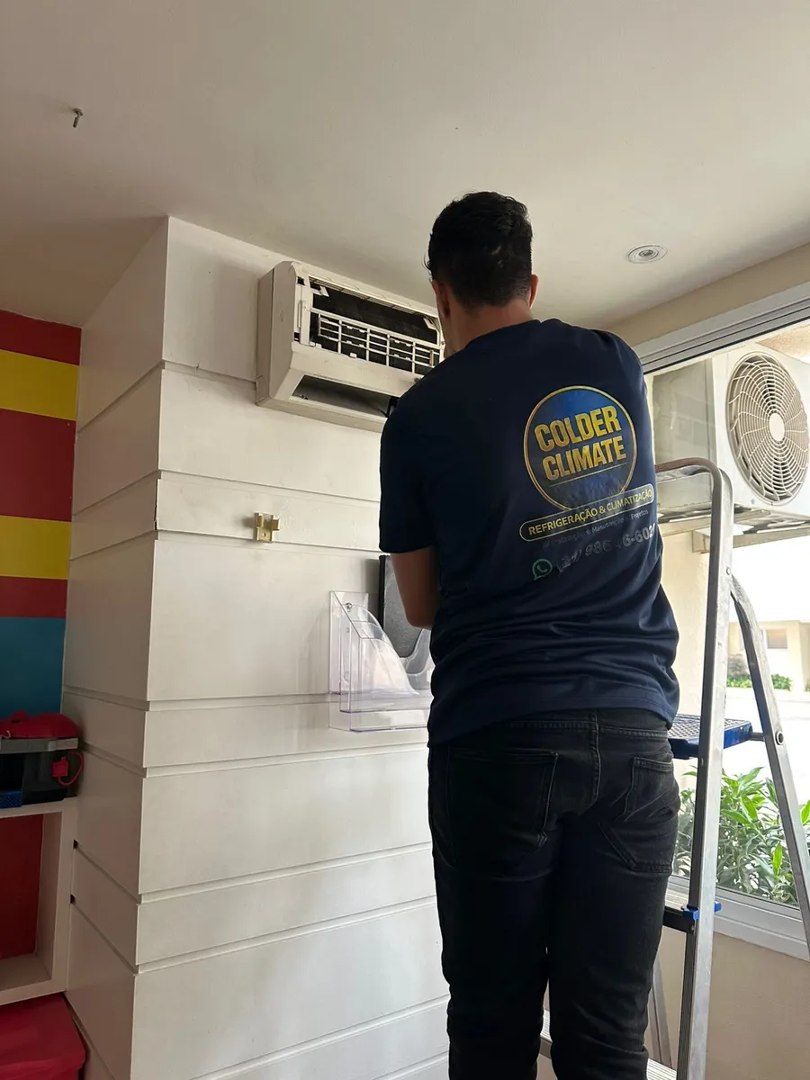 Técnico da Colder Climate com a camiseta da empresa trabalhando em um split instalado na parede